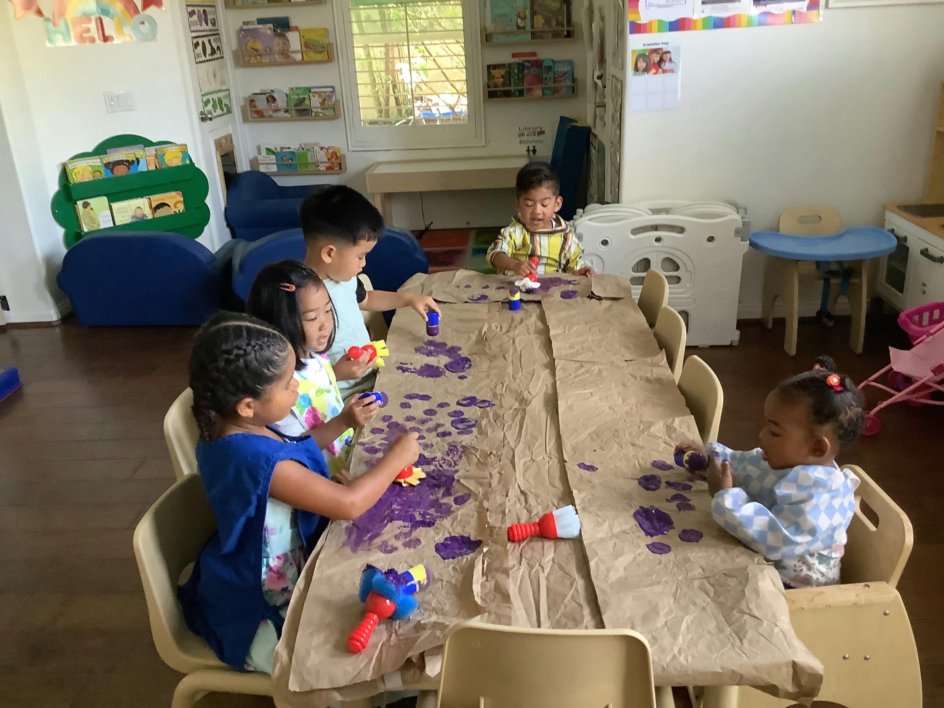 Children painting at a table in a classroom