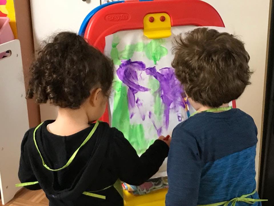 Two children painting on an easel