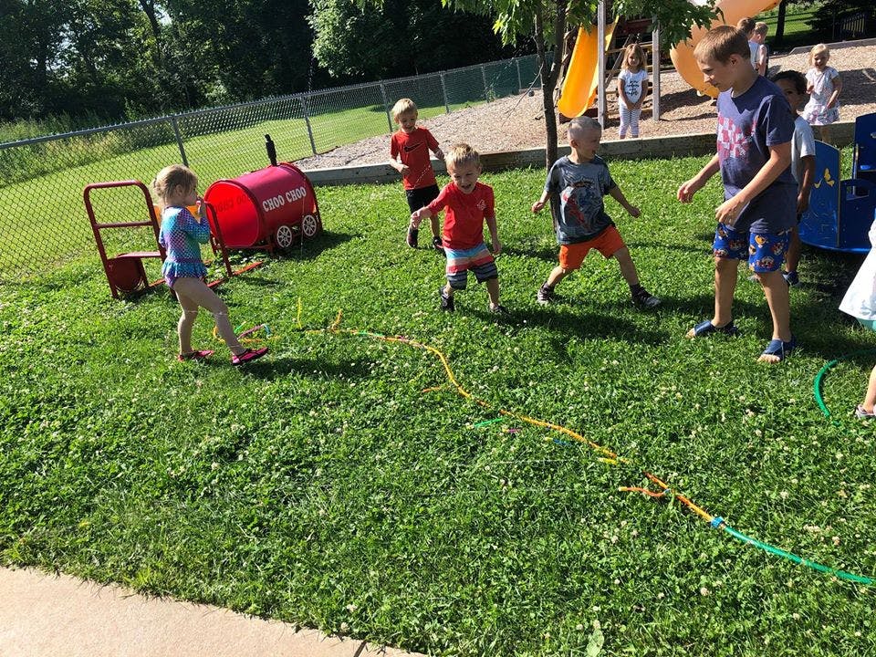 Children playing on a grassy area with playground equipment