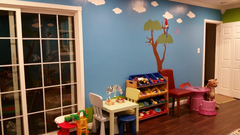 Children's playroom with blue walls, small tables, chairs, and toy storage