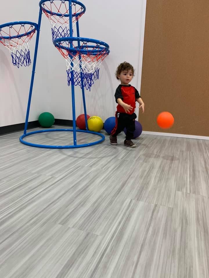 Child playing with a basketball near a toy hoop