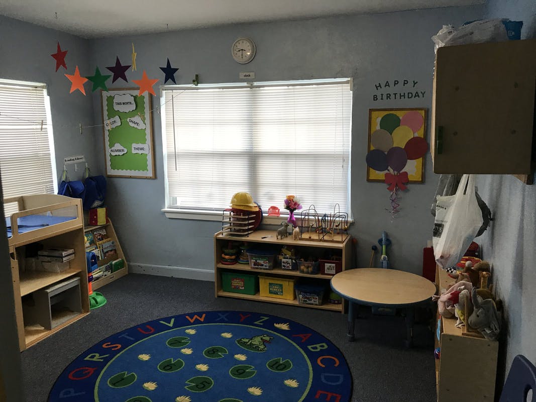Classroom with a blue rug, shelves, and a window