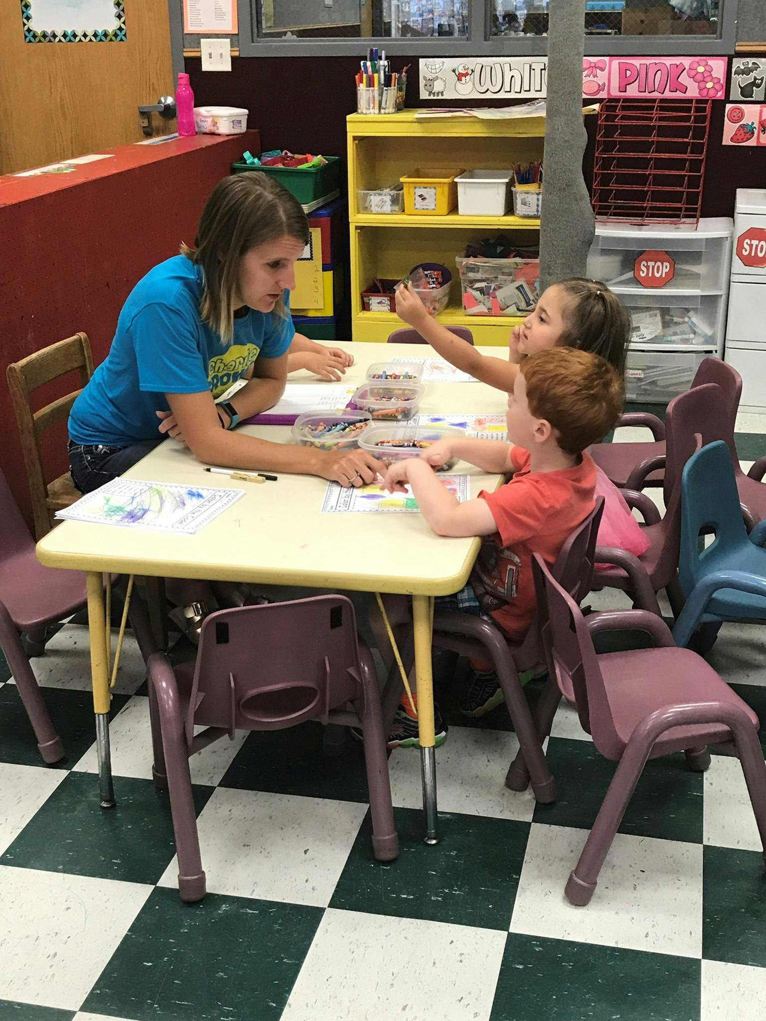 Adult and two children at a table in a classroom