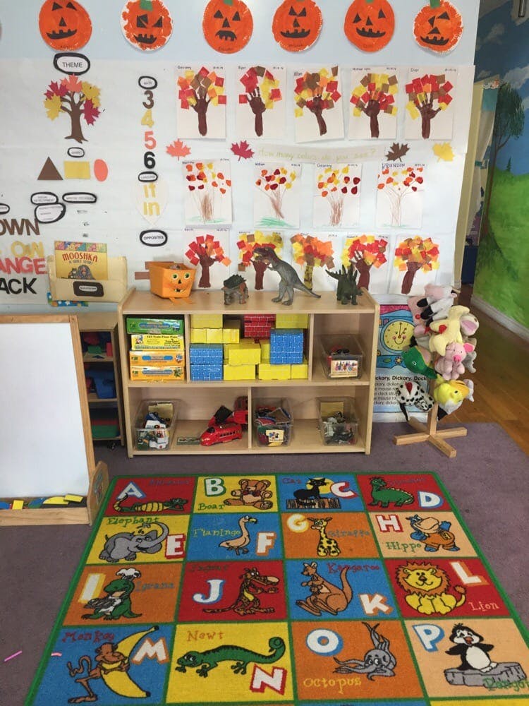 Classroom with fall-themed decorations, shelves of toys, and an alphabet rug