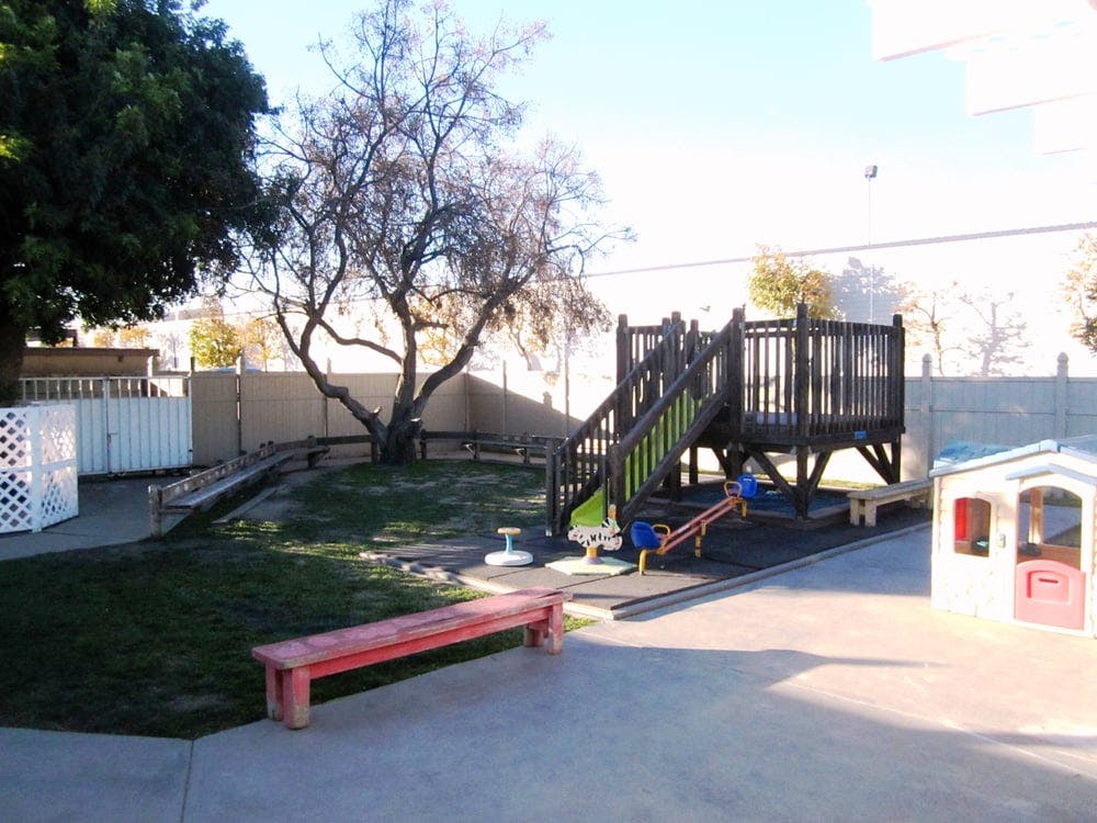 Outdoor playground with wooden structure, slide, seesaw, and small playhouse