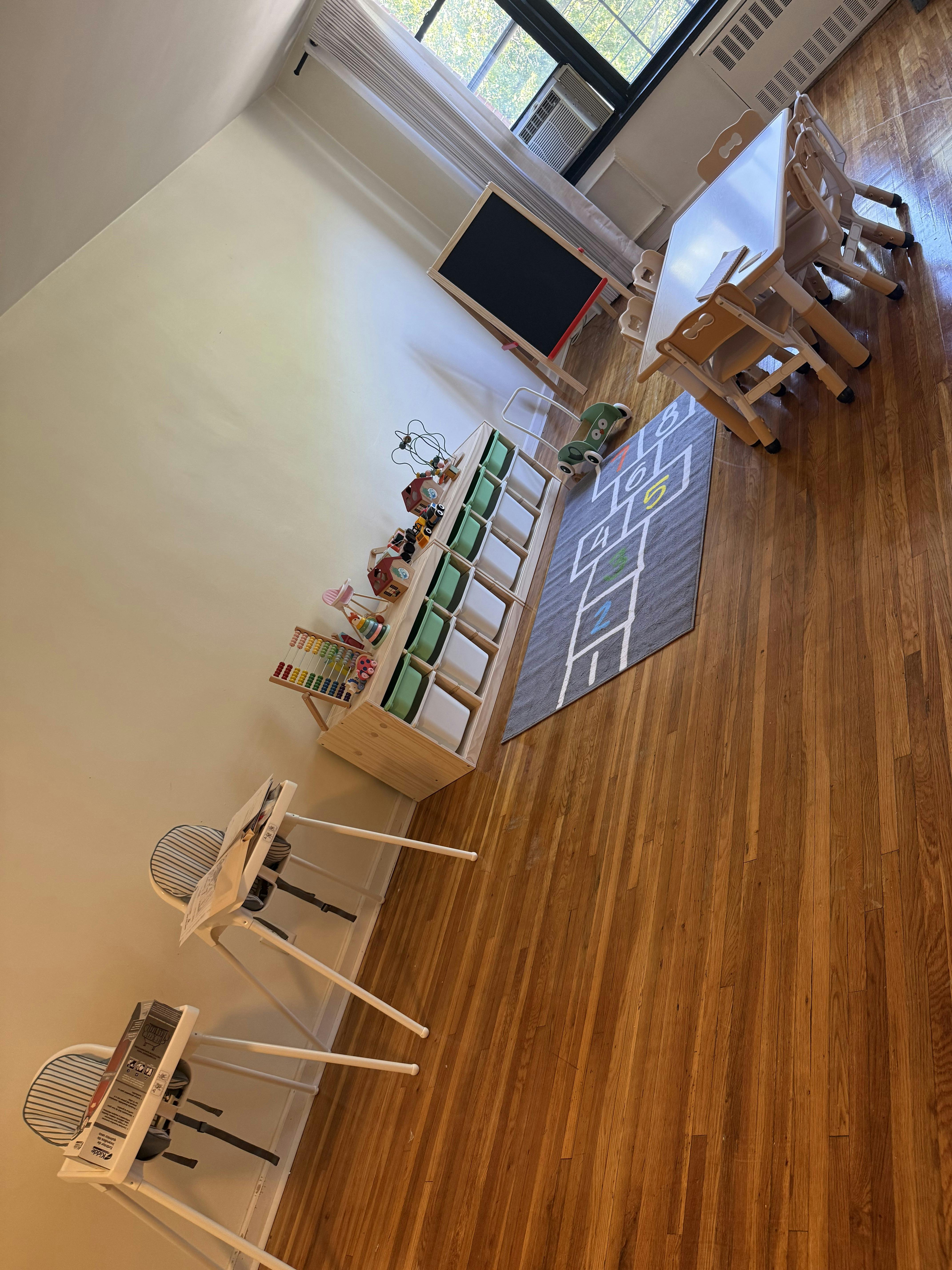 Classroom with small tables, chairs, and a hopscotch rug