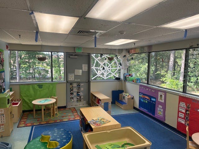 Classroom with child-sized table and chairs, windows overlooking trees