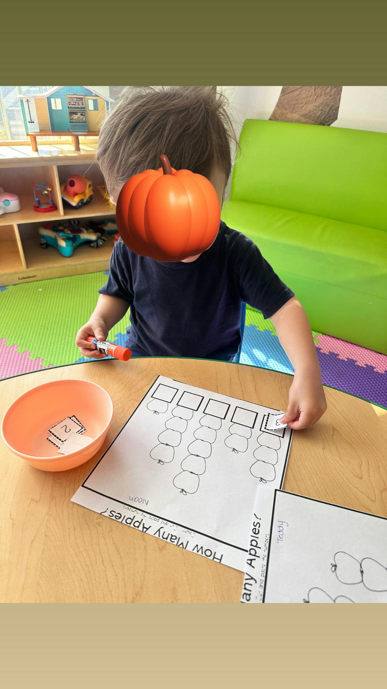 Child doing an activity with paper and glue stick at a table