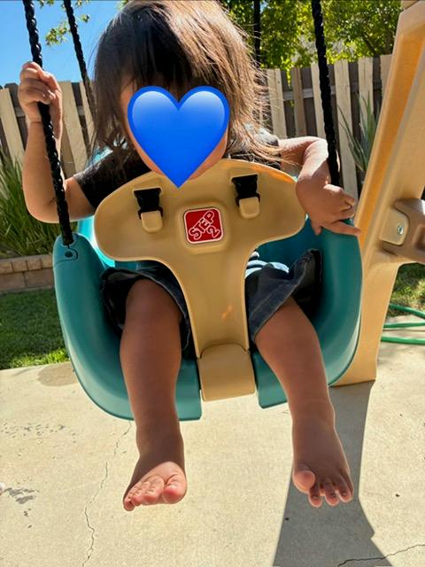 Child sitting in a plastic bucket swing