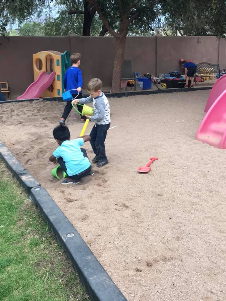 Children playing in a sandbox with toys