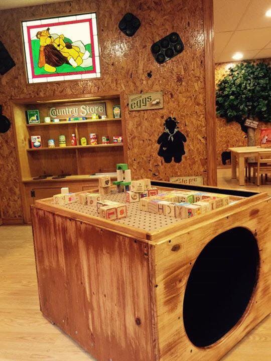 Wooden play area with blocks on a table and a "Country Store" sign