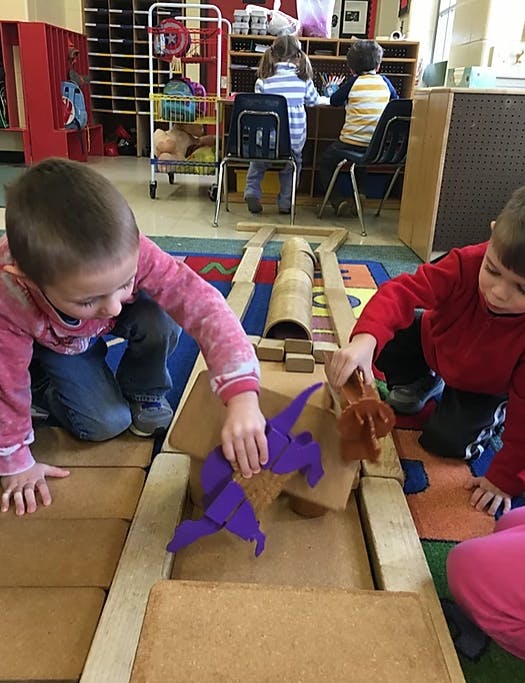 Two children playing with blocks and toys on the floor