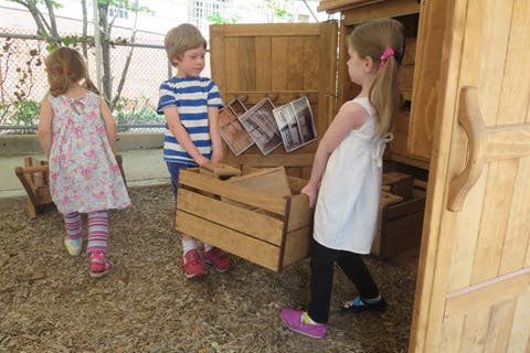Three children playing with wooden crates