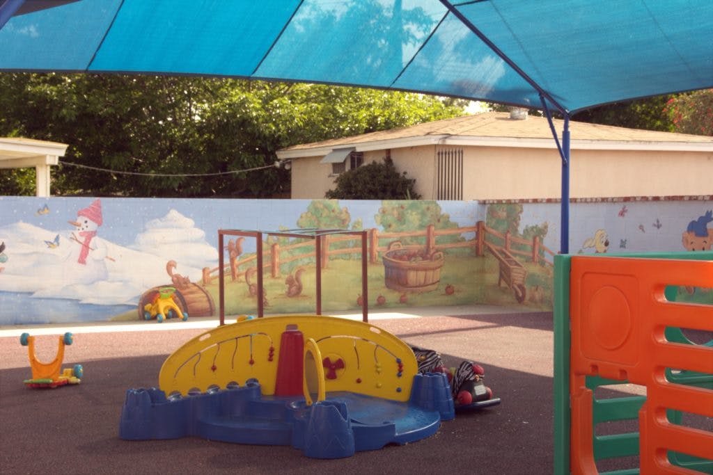 Outdoor playground with colorful play structures and a painted wall