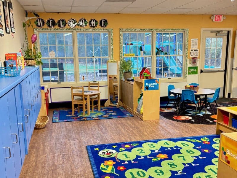 Classroom with small tables and chairs, storage cabinets, and play areas