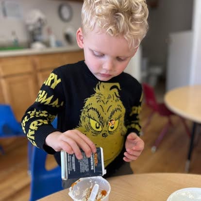 Child pouring from a small carton into a cup