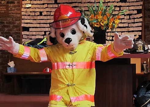 Person in a dog mascot costume wearing a firefighter uniform