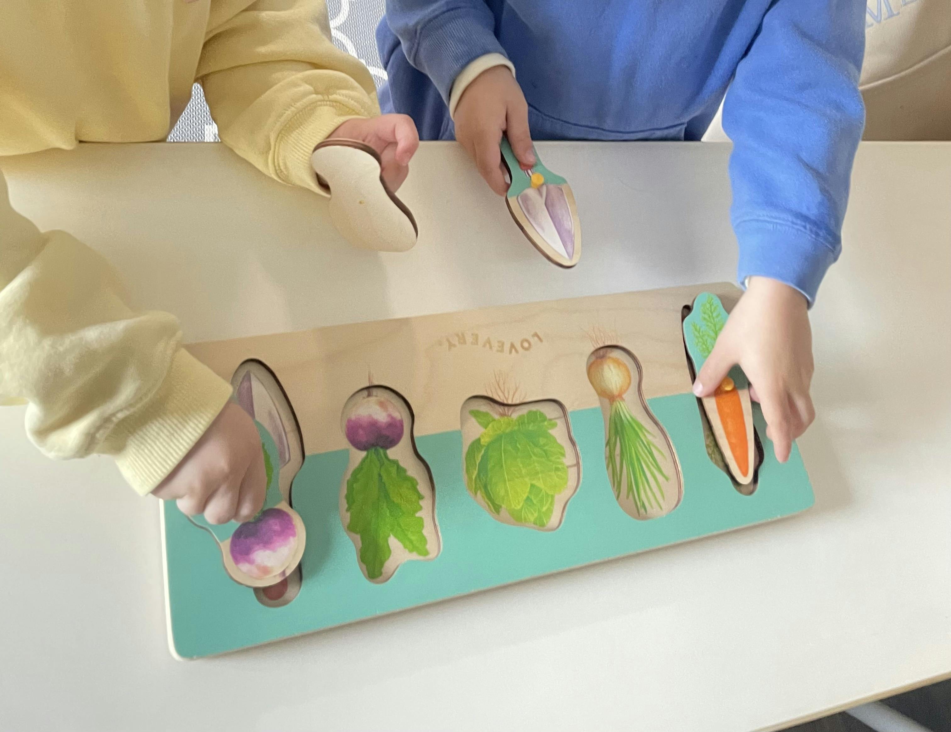 Two children playing with a wooden puzzle of vegetables