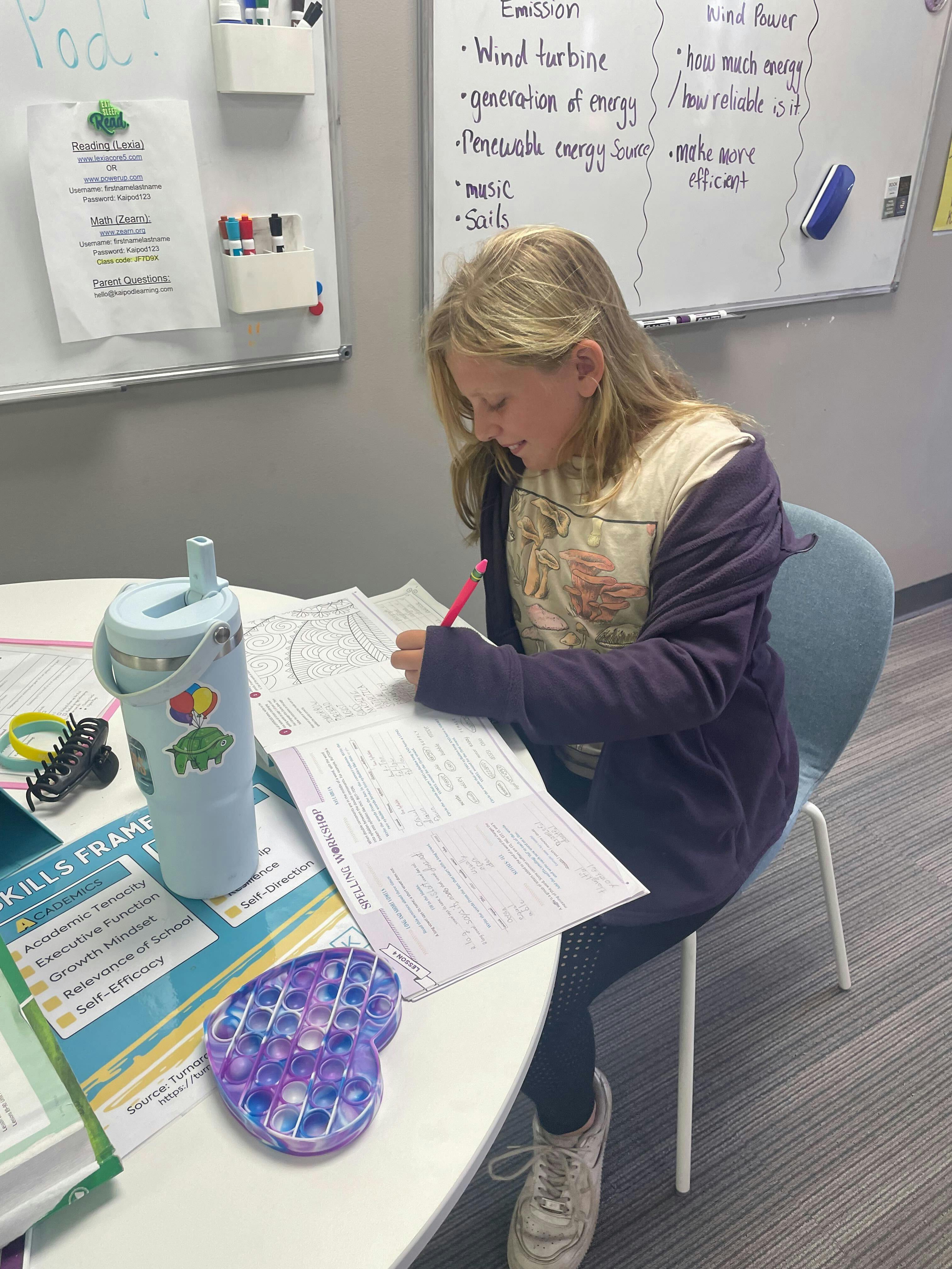 Child writing at a desk in a classroom