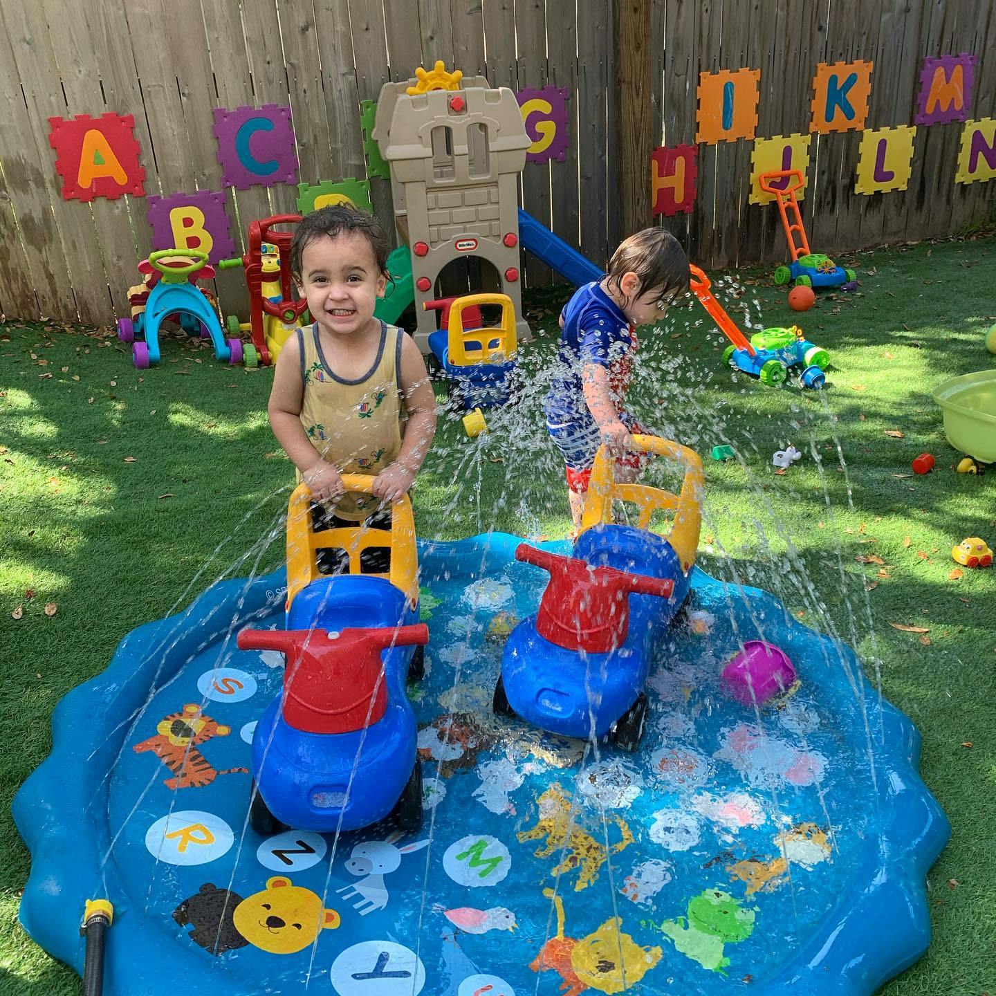 Two children playing in a splash pad with ride-on toys