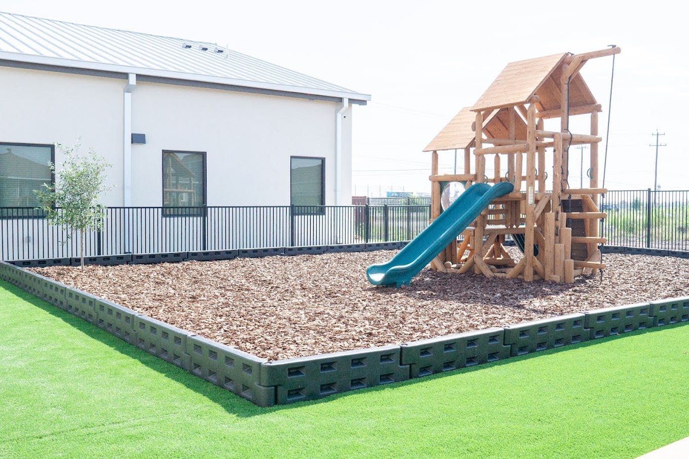 Wooden playground set with a slide on a wood chip surface