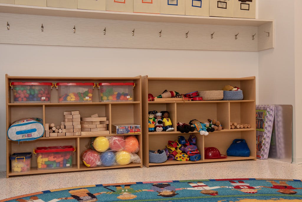 Classroom shelving with bins of colorful toys and wooden blocks