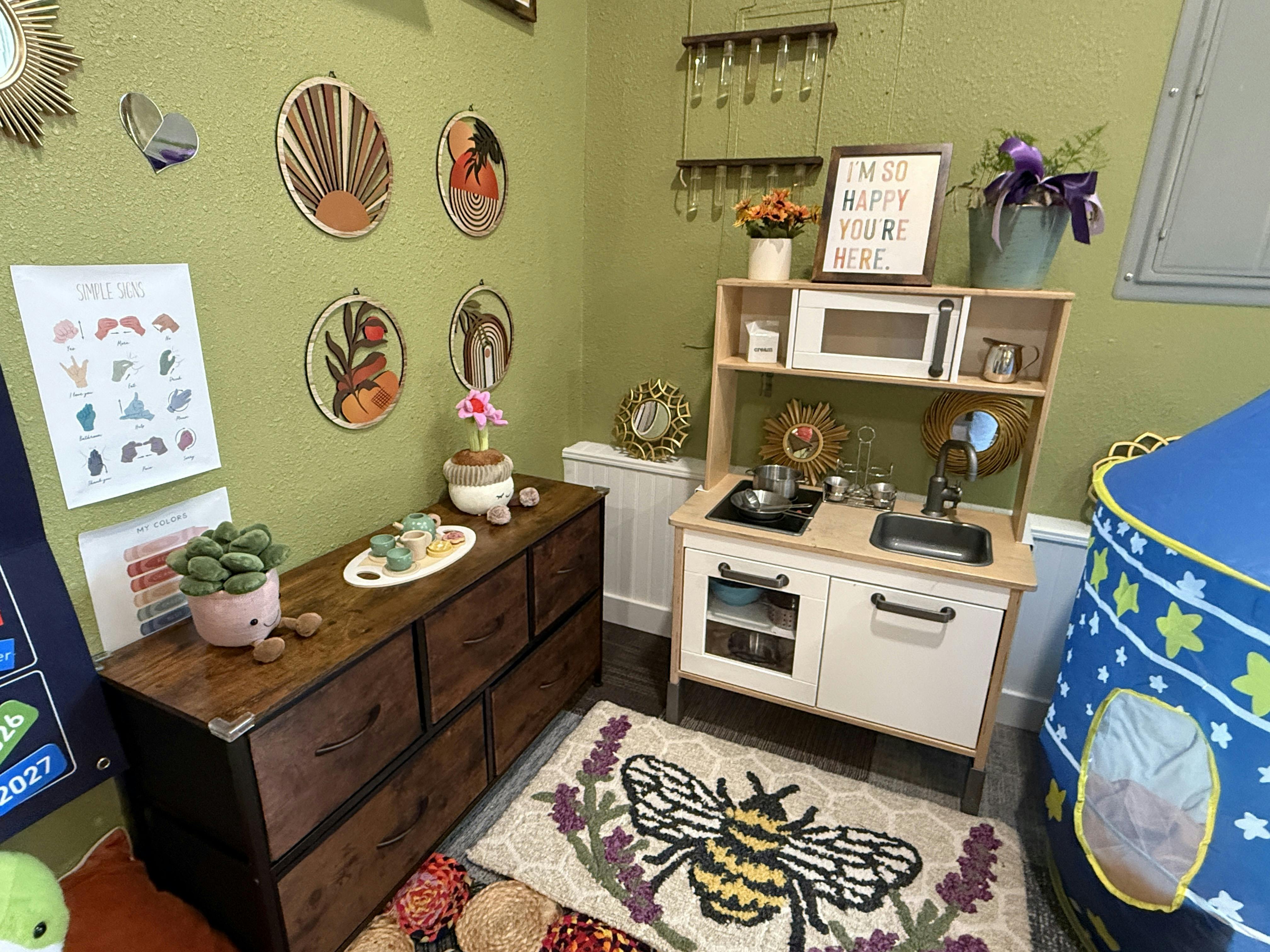 Children's play kitchen and dresser in a room with green walls