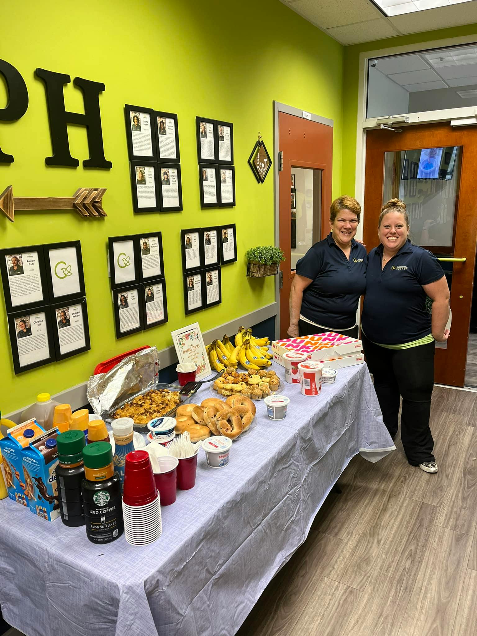 Two people standing behind a table with food and drinks