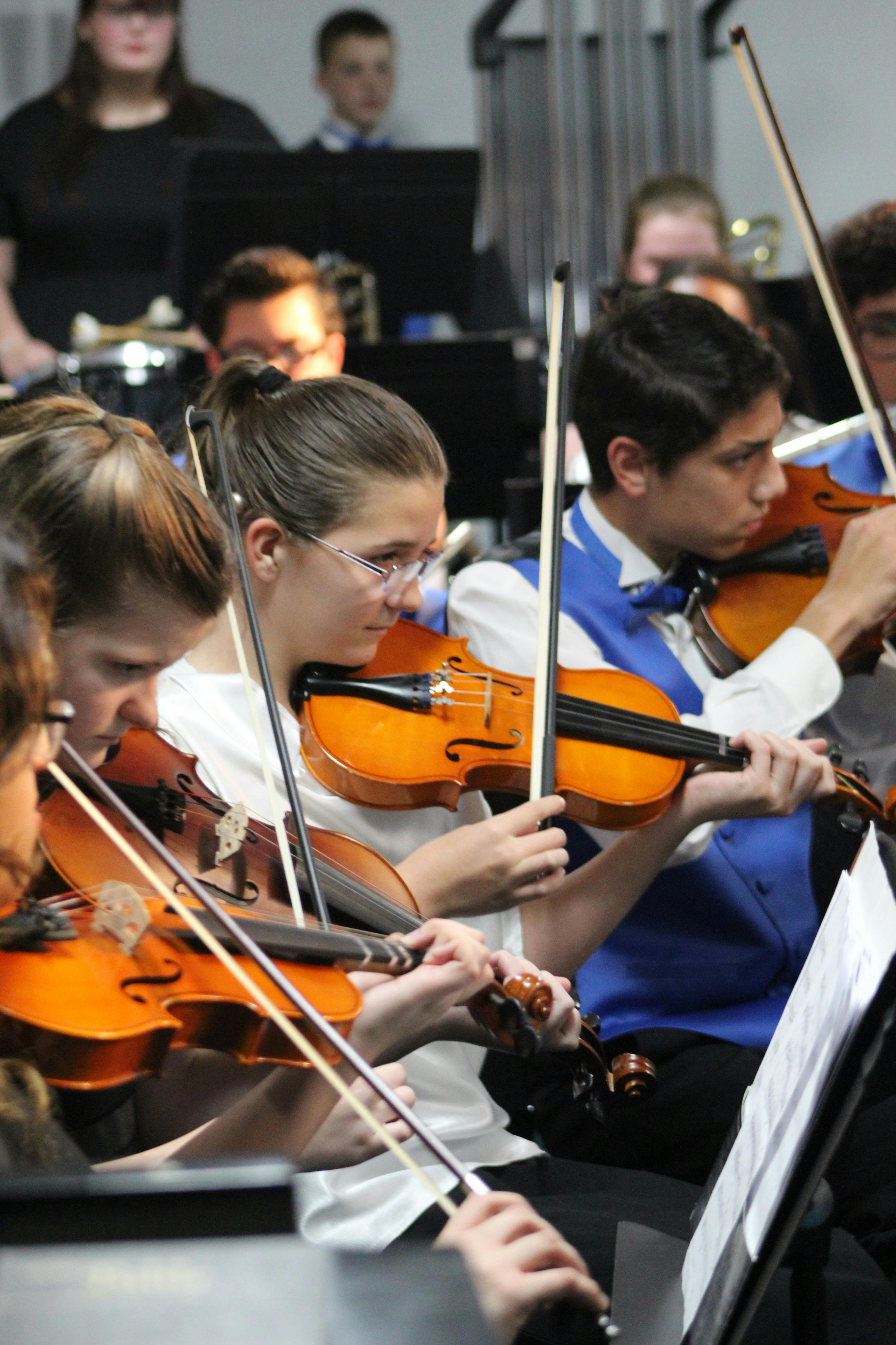 Teens playing violins in an orchestra