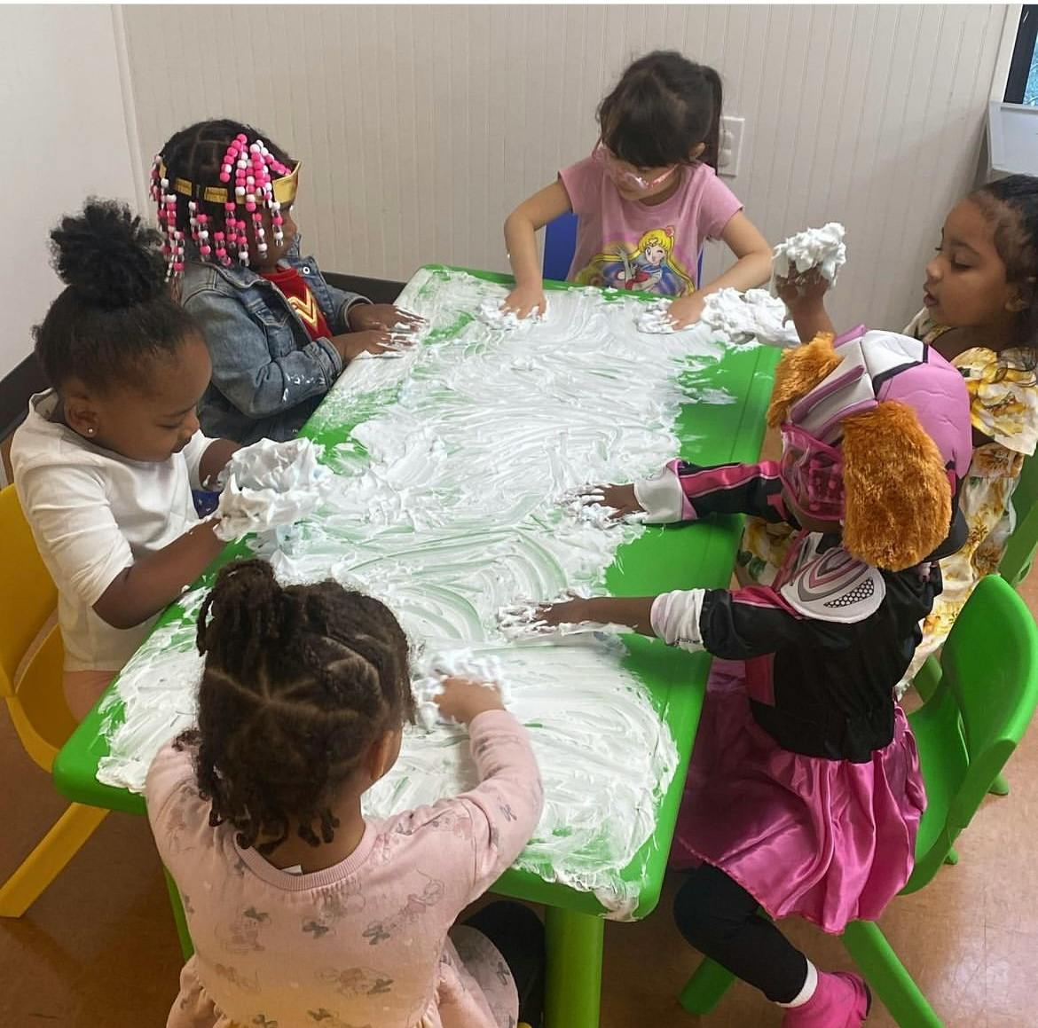 Children playing with shaving cream on a green table