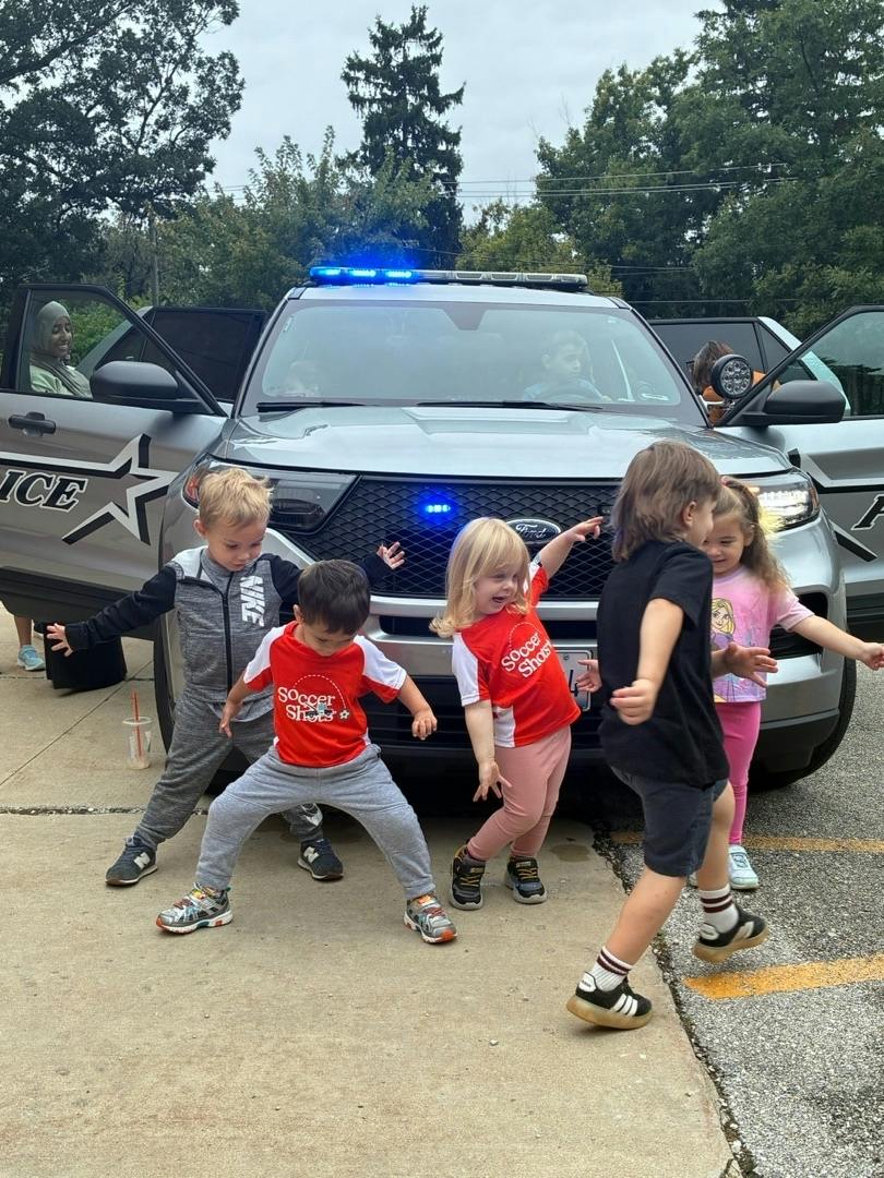 Group of children dancing in front of a police vehicle