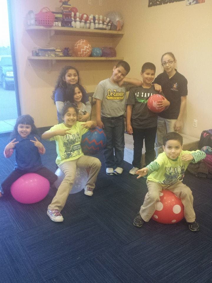 Group of children and adults posing with balls, some sitting on bouncy balls