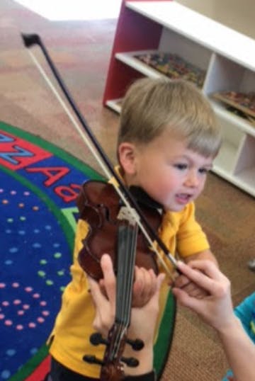 Child playing a violin with assistance