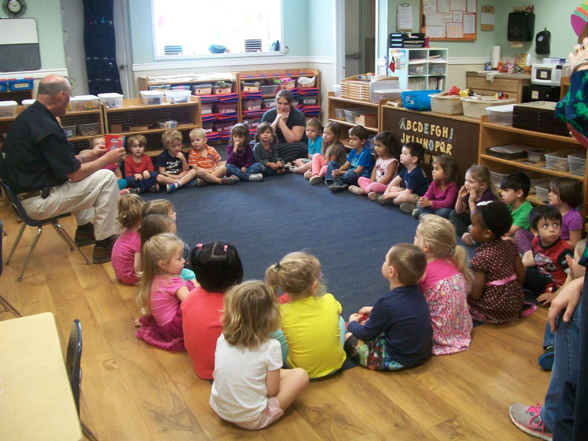 Adults and children sitting in a circle on the floor in a classroom