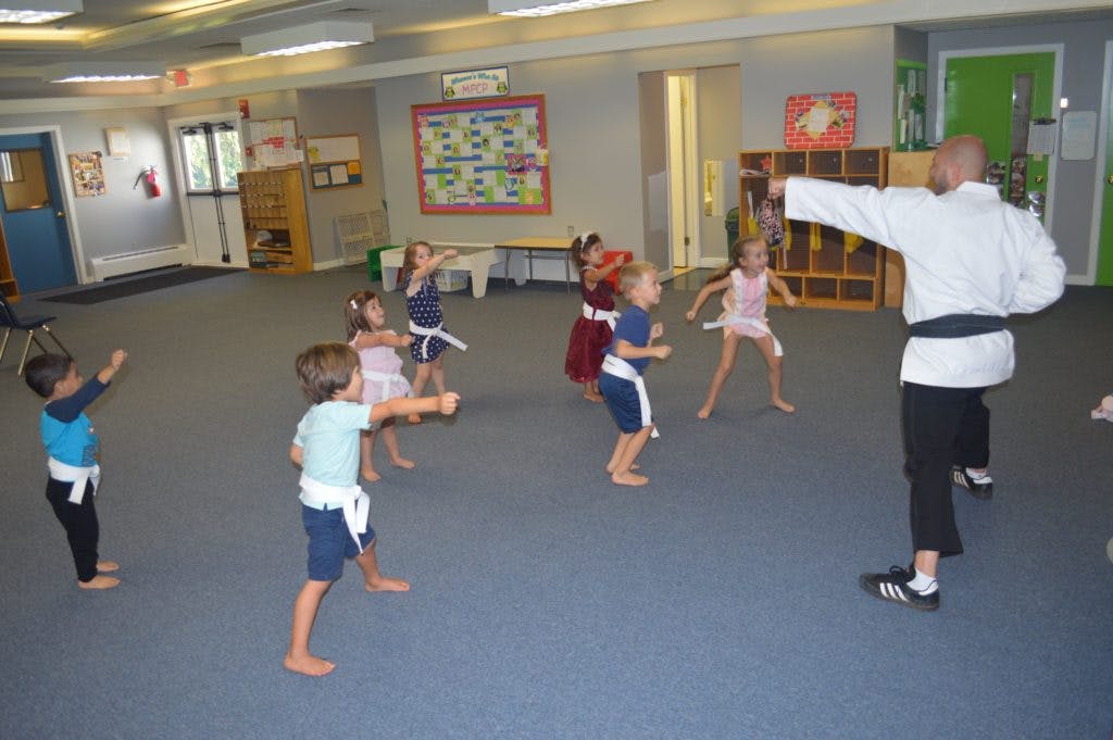 Adult teaching children martial arts in a classroom