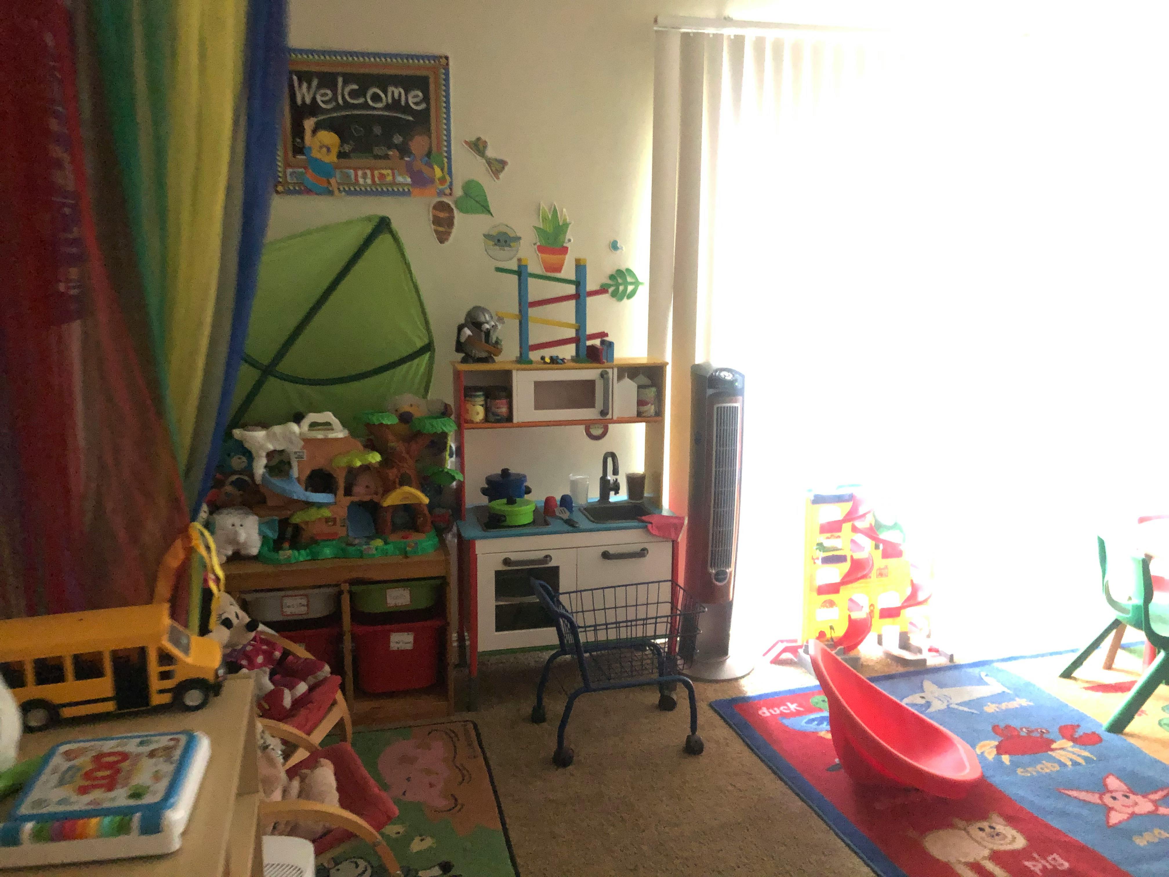 Playroom with toy kitchen, school bus, and colorful rug