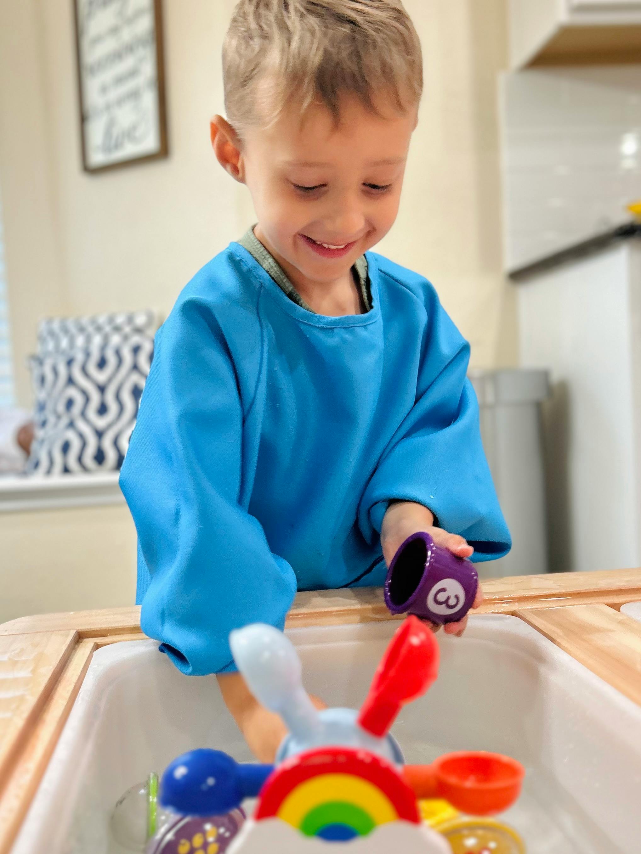 Child in blue smock playing with water toys