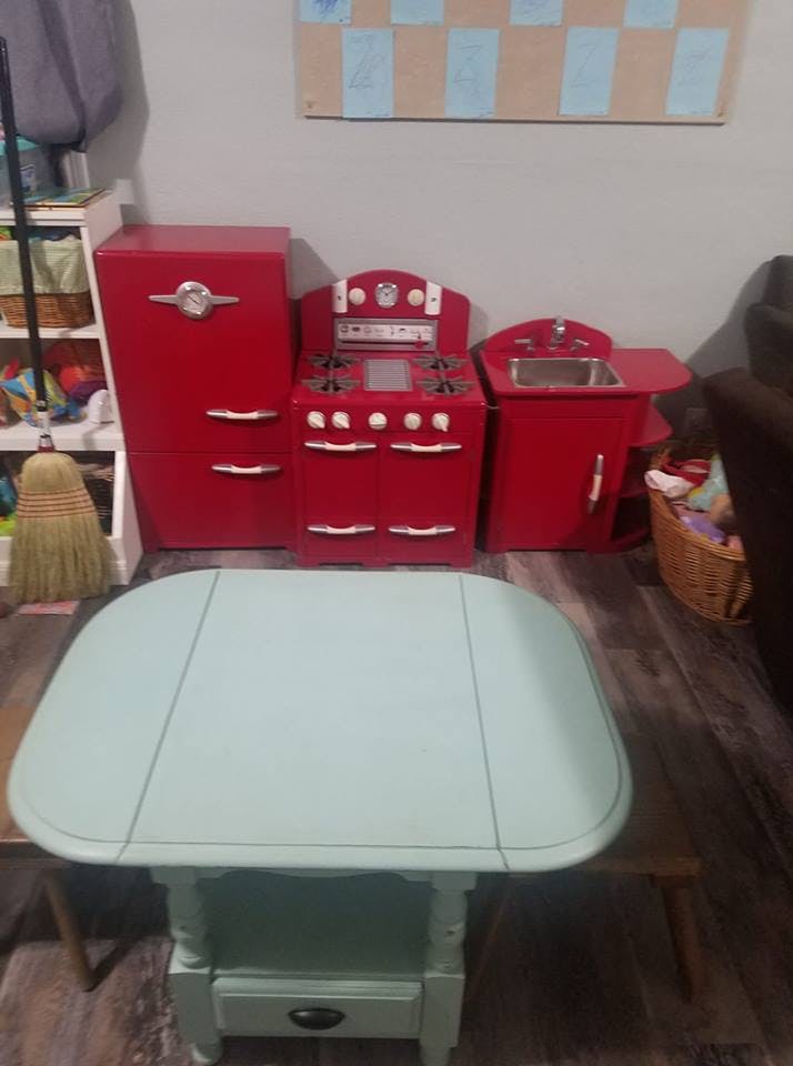 Red toy kitchen set with a refrigerator, stove, and sink