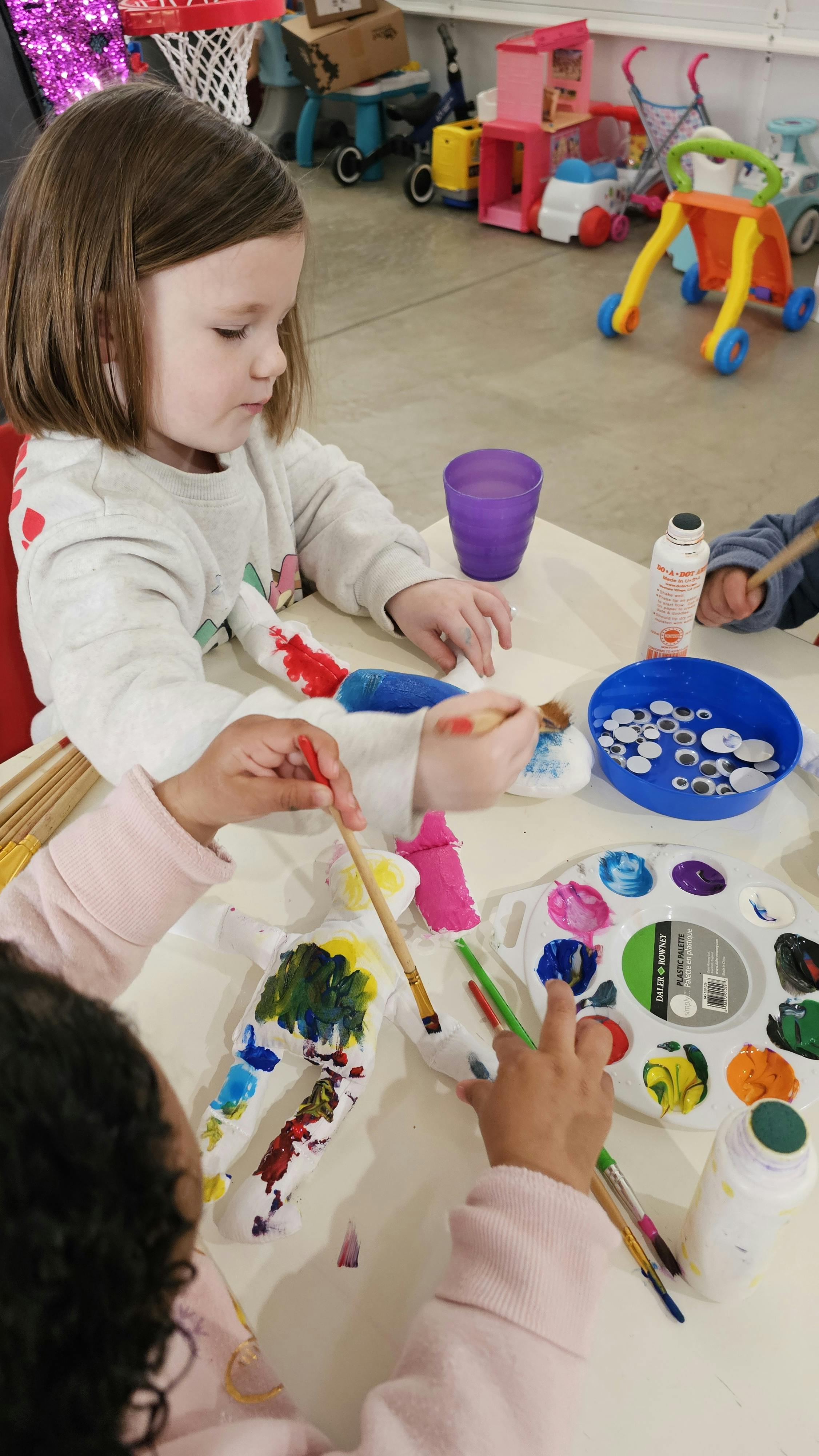 Two children painting crafts at a table