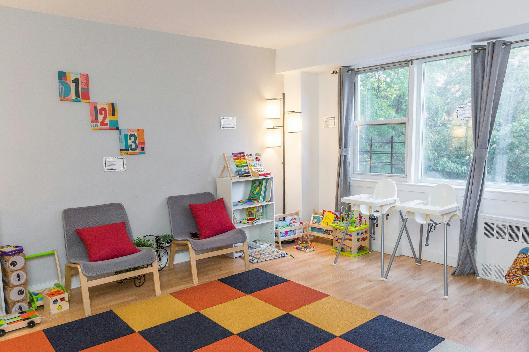 Playroom with two chairs, a bookshelf, and a colorful checkered mat