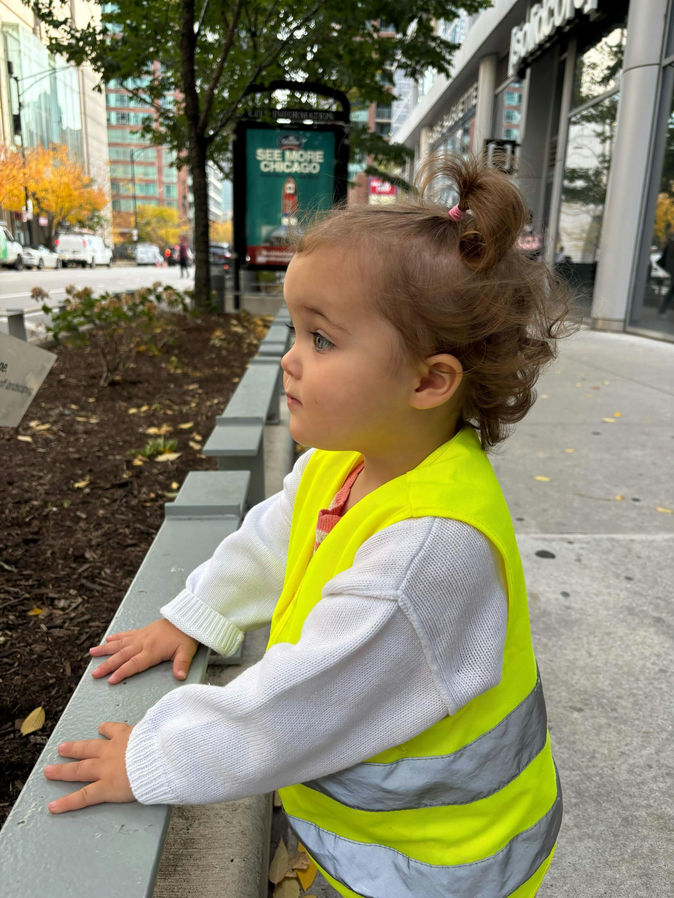 Child in a safety vest looking out from a ledge