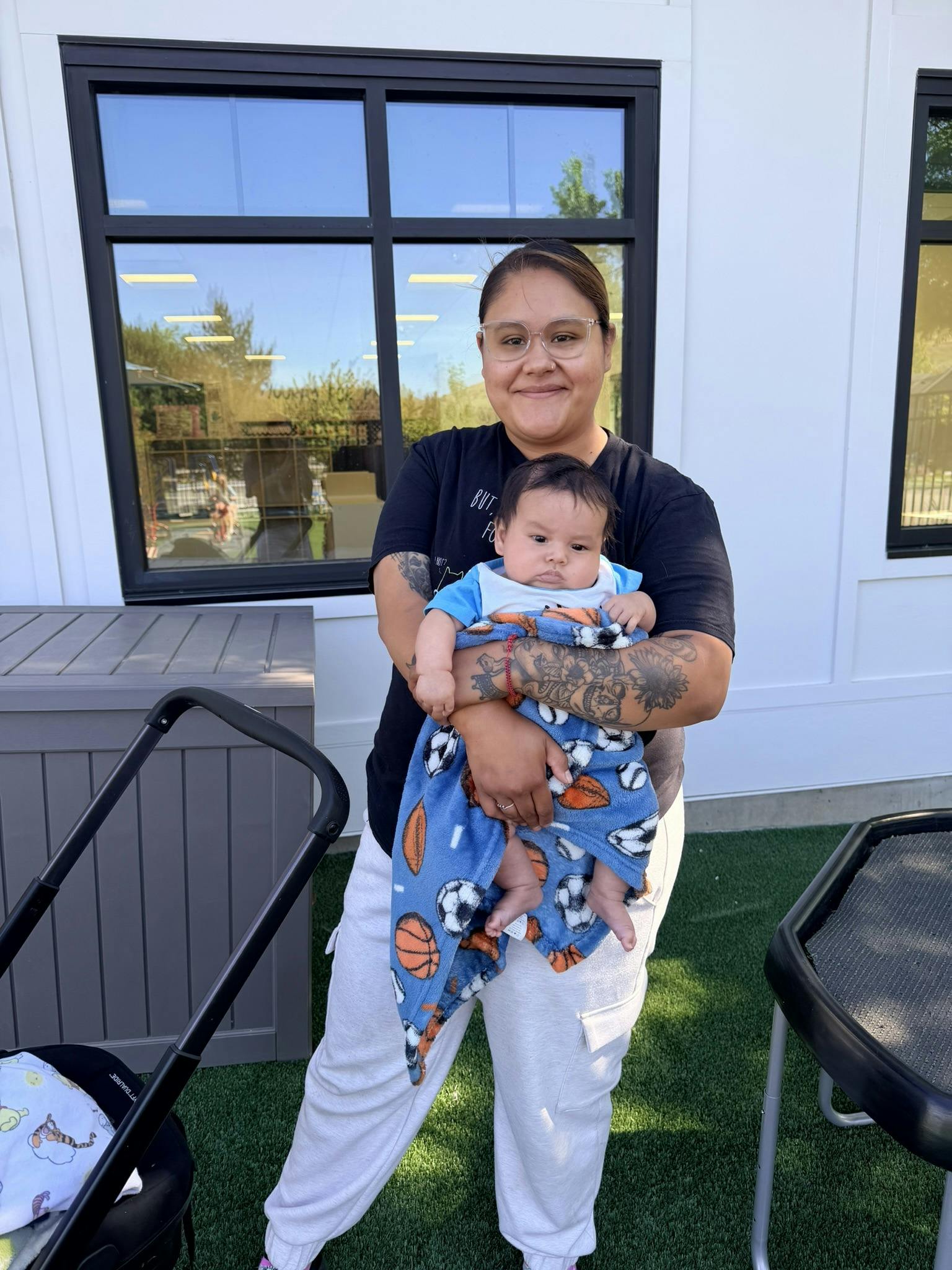 A person holding an infant wrapped in a sports-themed blanket