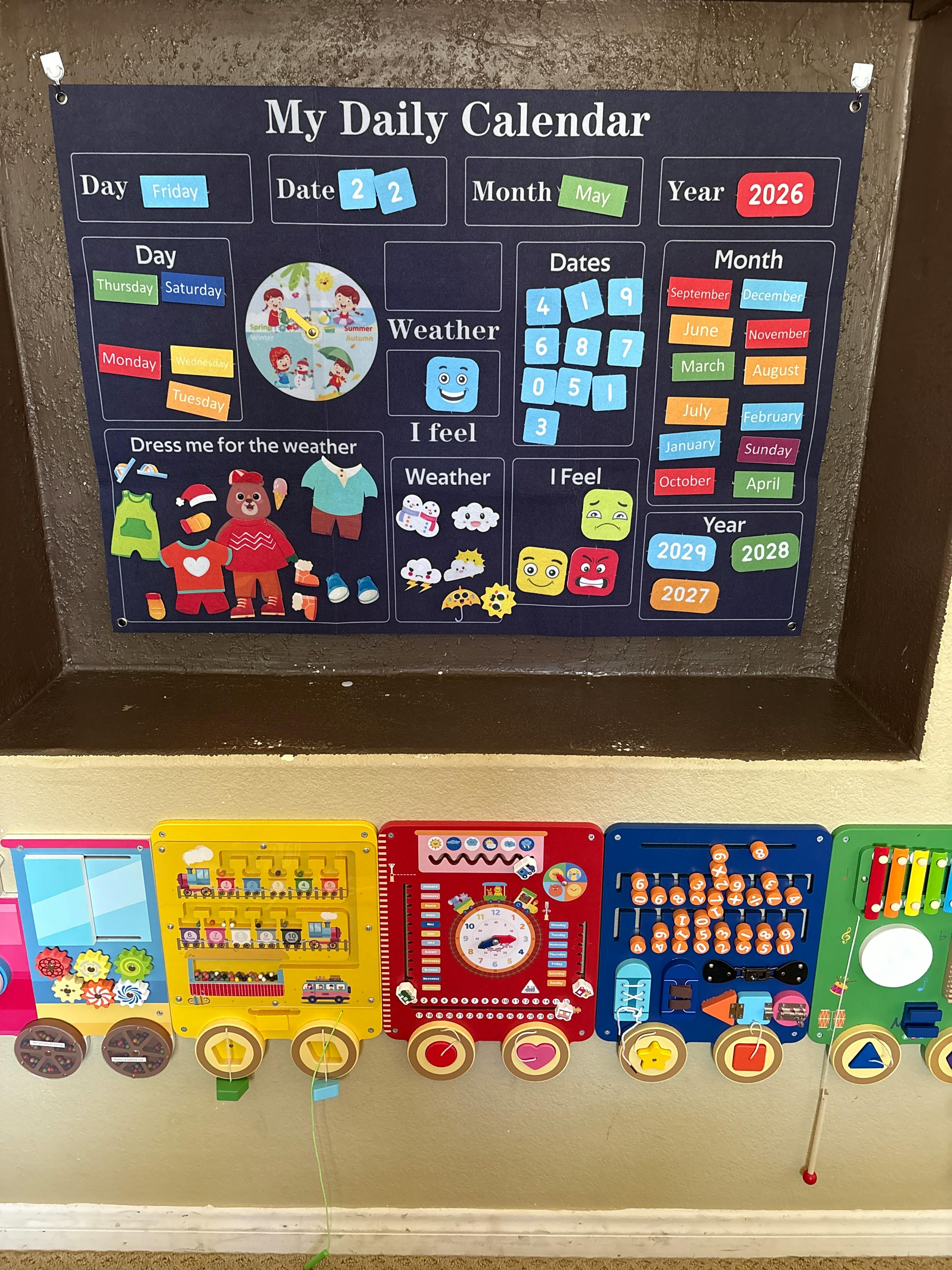 A daily calendar with magnetic pieces for date, month, year, weather, and feelings, next to busy board toys