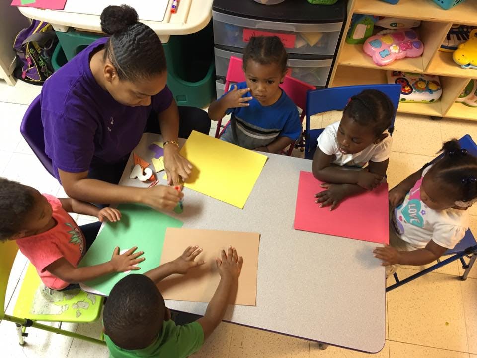 Adult and children at a table with construction paper