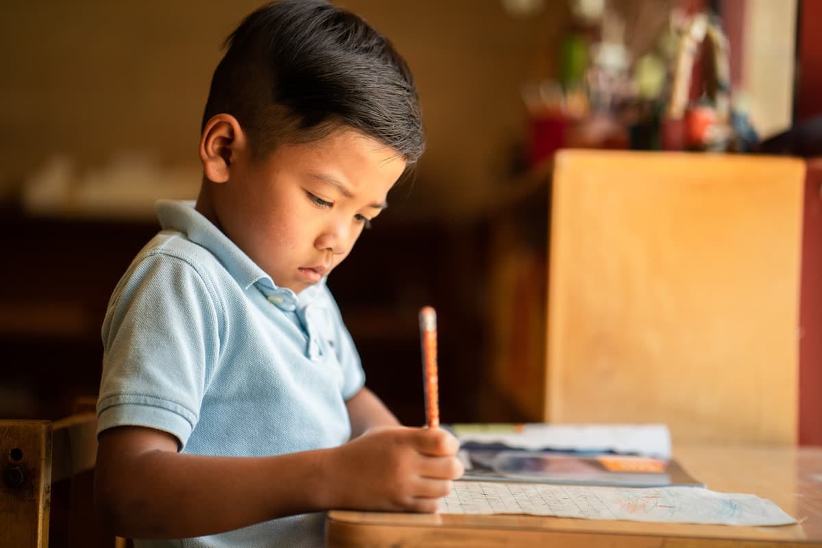 Child writing with a pencil at a table