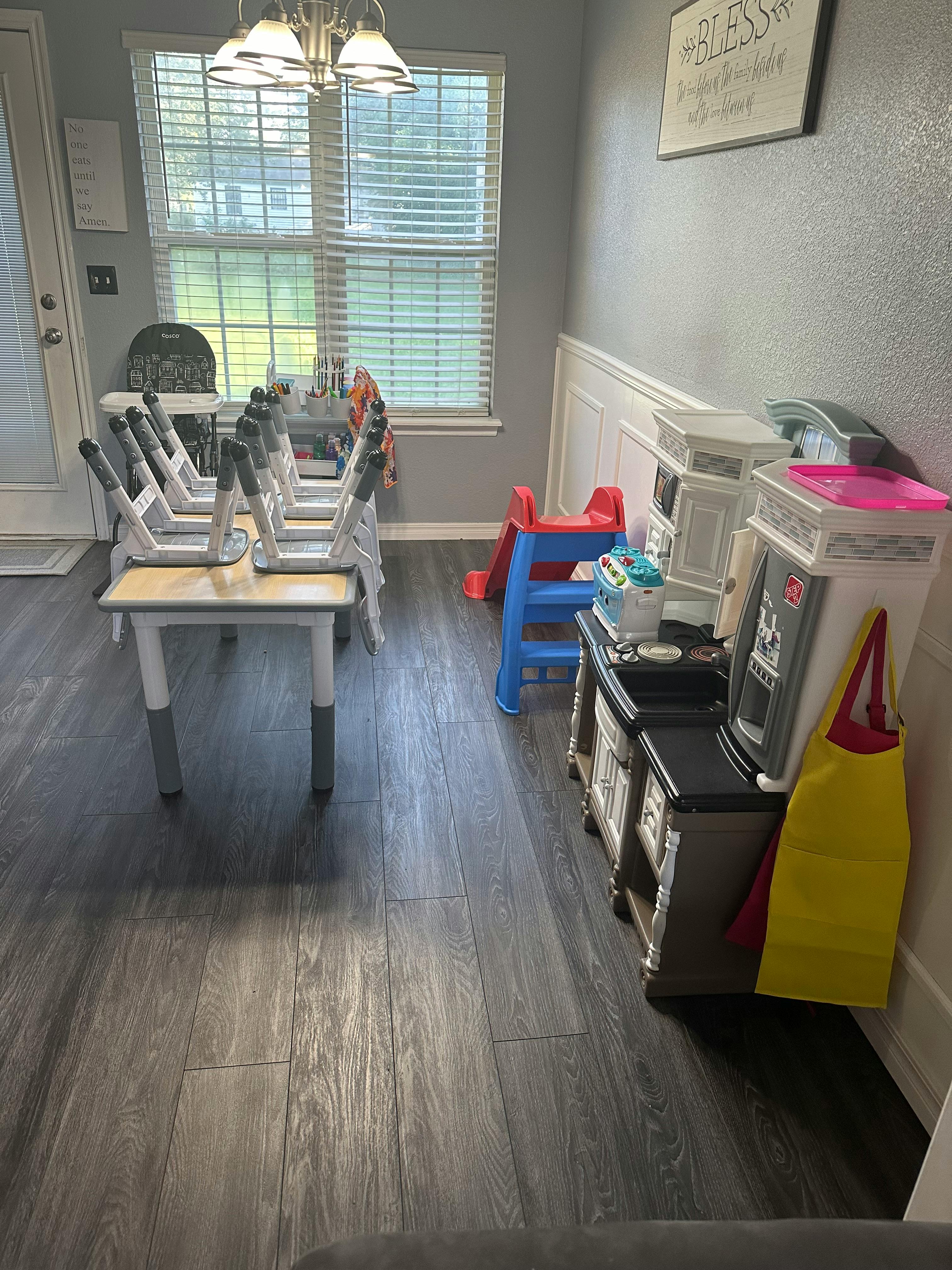 Dining table with chairs, children's slide, and toy kitchen set in a room