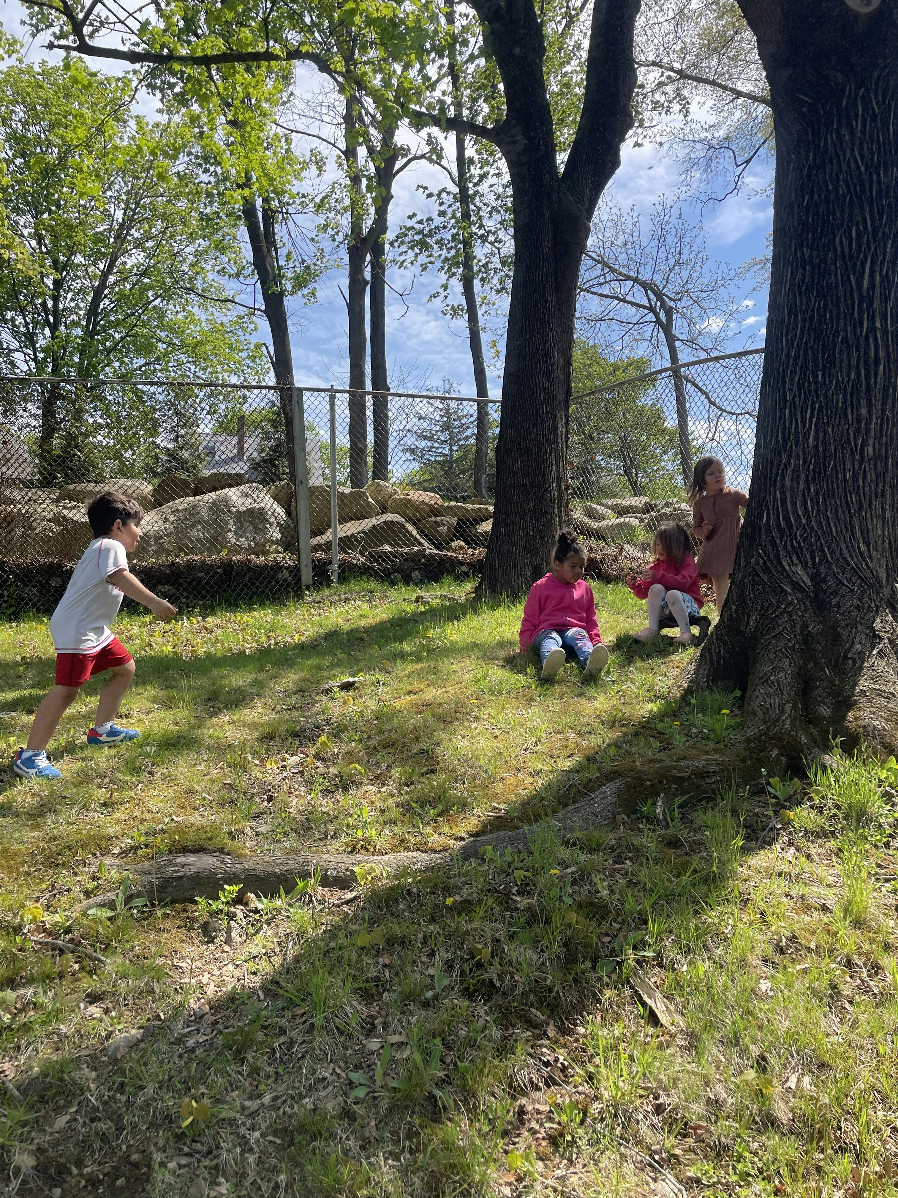 A child running toward other children sitting near trees in a park