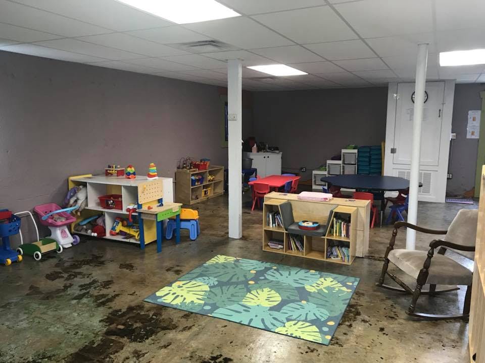 Playroom with toys, tables, chairs, and a rug