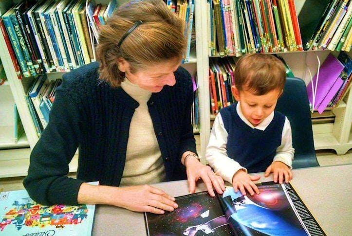 Person and child looking at a book in a library