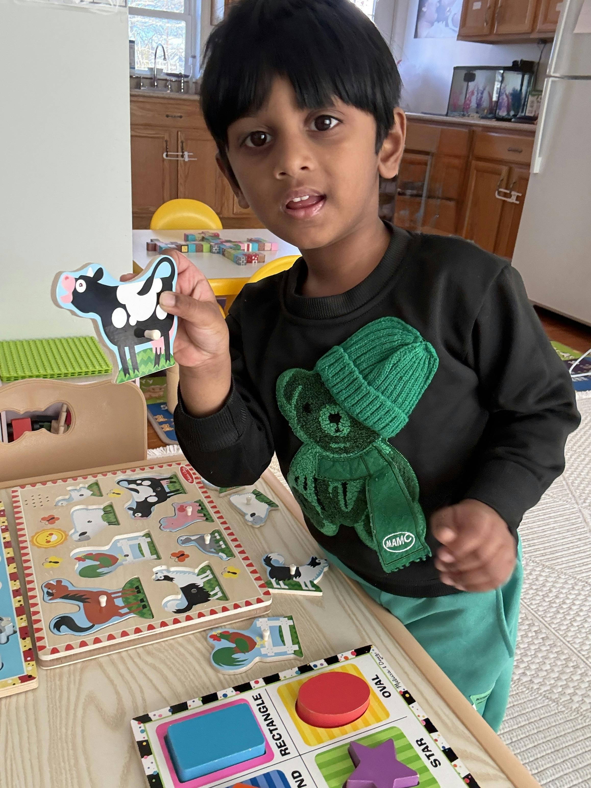 Child holding up a wooden cow puzzle piece